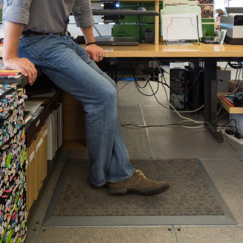 employee standing on mat while working on a standup desk