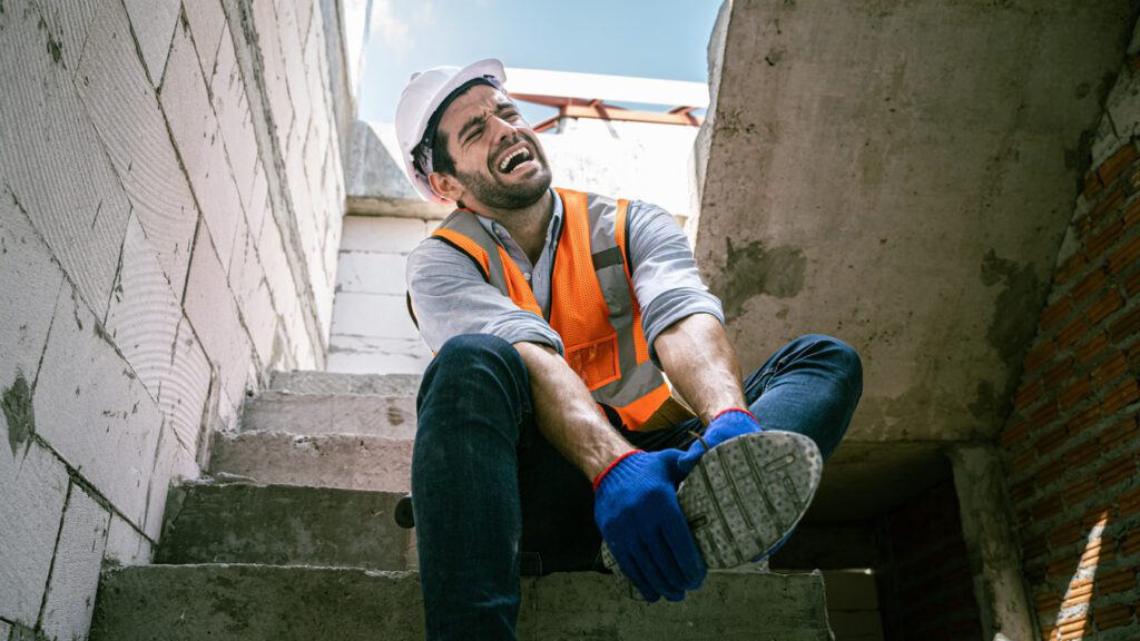 Construction worker in pain grabbing foot