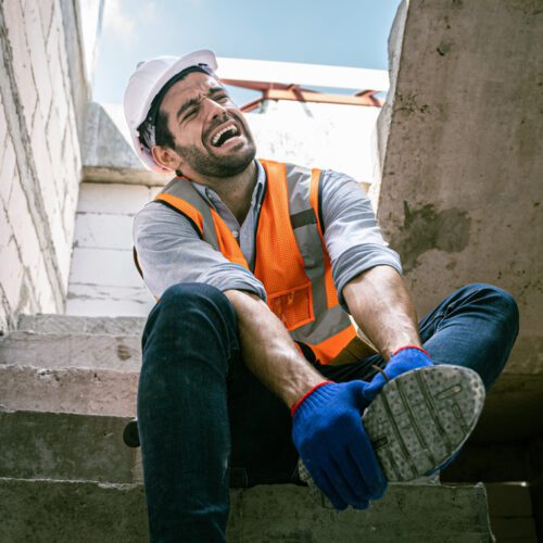 Construction worker in pain grabbing foot