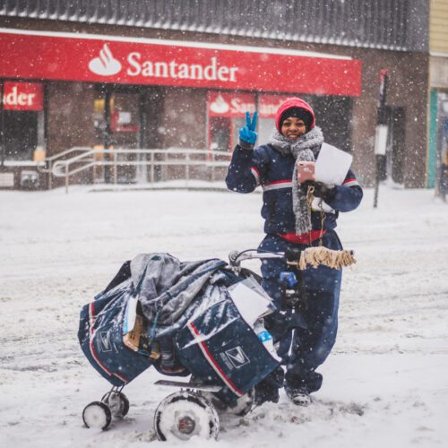 Postal service employee delivering mail in snow