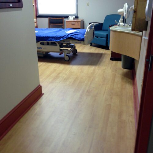 A hospital room with a bed where SmartCells Flooring is used as the underlayment