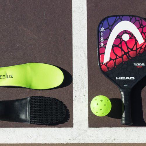 Zelus Insoles laying on pickleball court next to paddle and ball